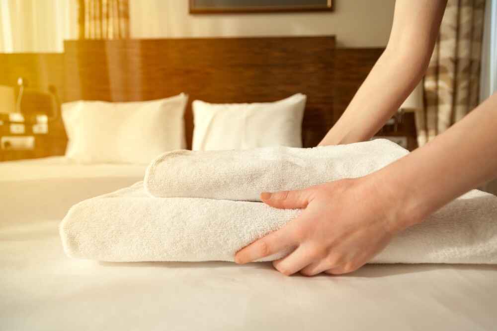 Maid putting towels on bed