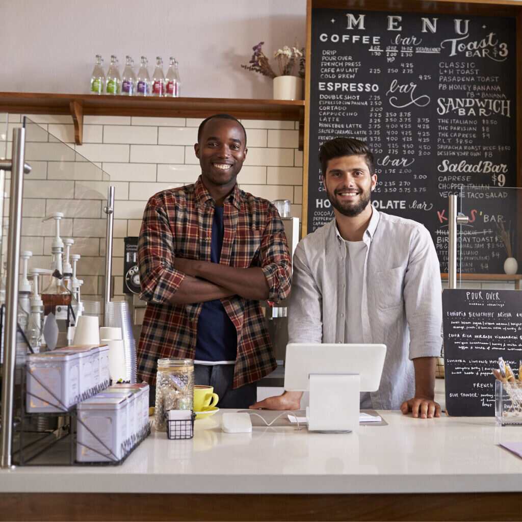 Two men standing behind coffee shop counter